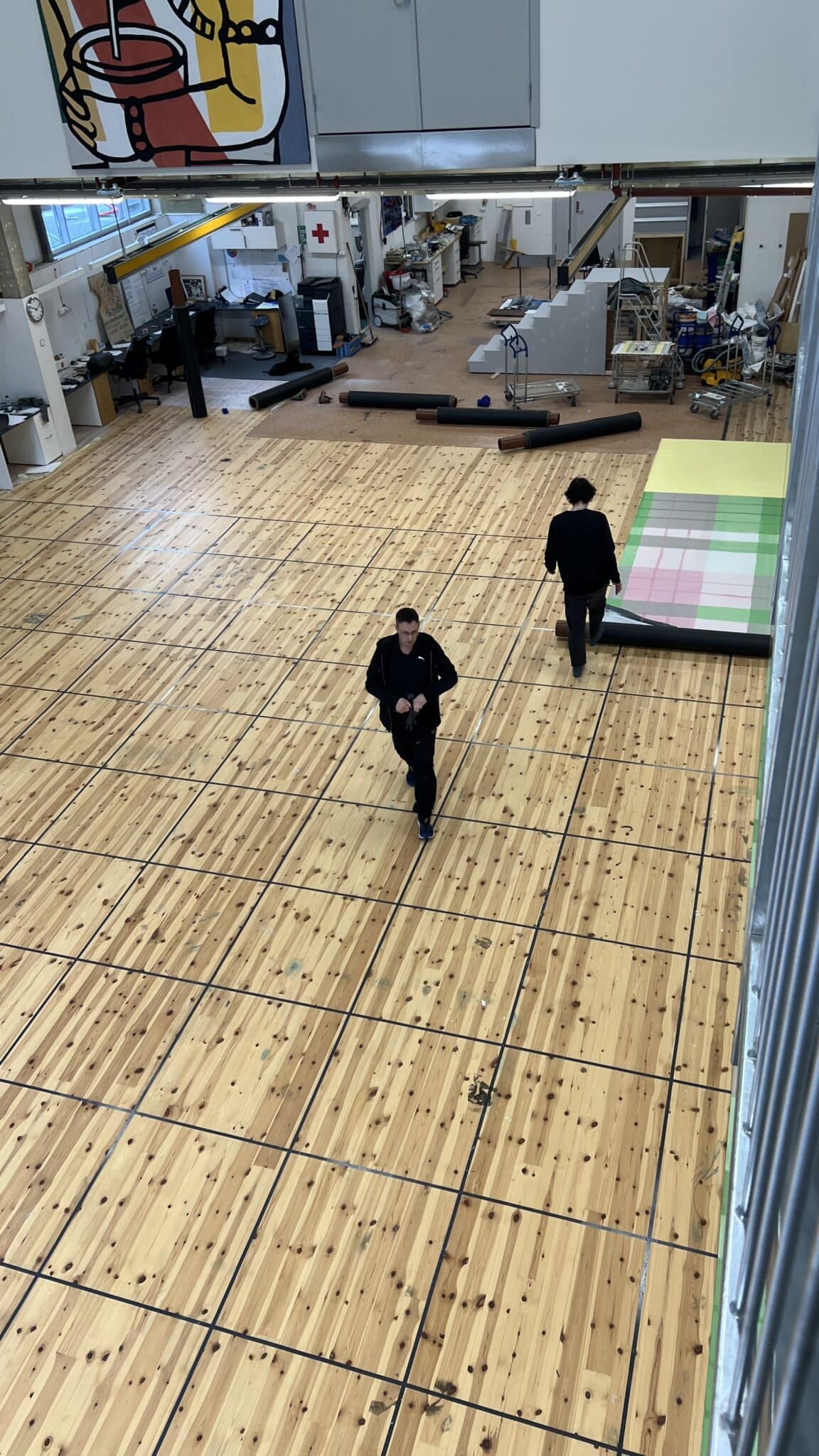 Wide view of the workshop after the floor has been rolled up, showing the wooden surface beneath. Oversiktsbilde av malersalen etter at gulvet er rullet sammen, med tregulvet under synlig.